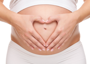Augmentation mammaire et désir d'enfant : faut-il attendre ou non ? 13 a pregnant woman holding her hands in a heart shape on her belly