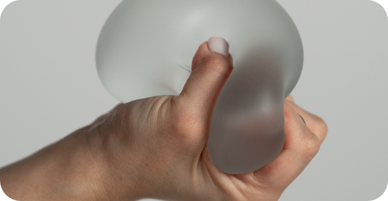 Motiva® Preservé™ 13 a hand holding a silicone breast implant