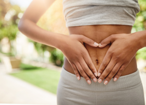Abdominoplastie vs liposuccion 9 a woman with her hand on her stomach, making the shape of a heart